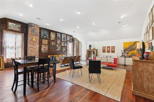 dining area with wood-type flooring, vaulted ceiling, and wooden walls