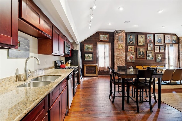 kitchen with light stone counters, appliances with stainless steel finishes, vaulted ceiling, dark hardwood / wood-style floors, and sink