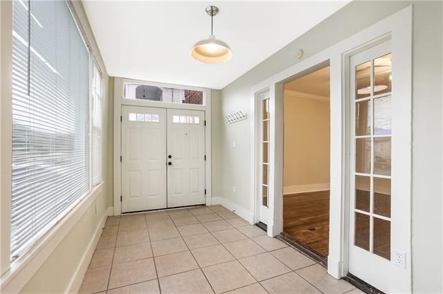 foyer entrance with crown molding and light tile patterned floors