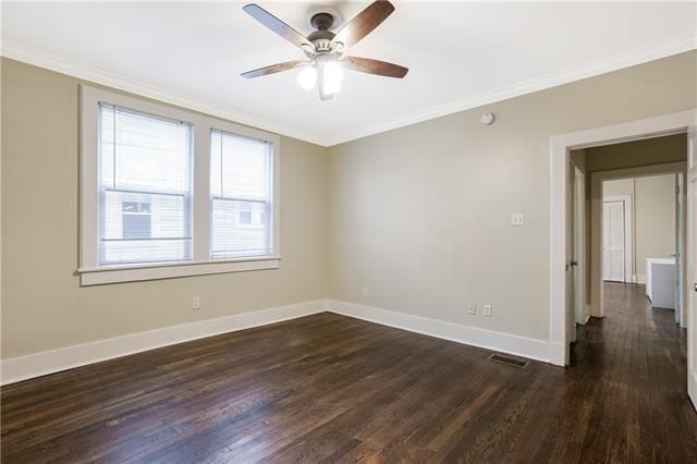 empty room featuring crown molding, dark wood-type flooring, and ceiling fan