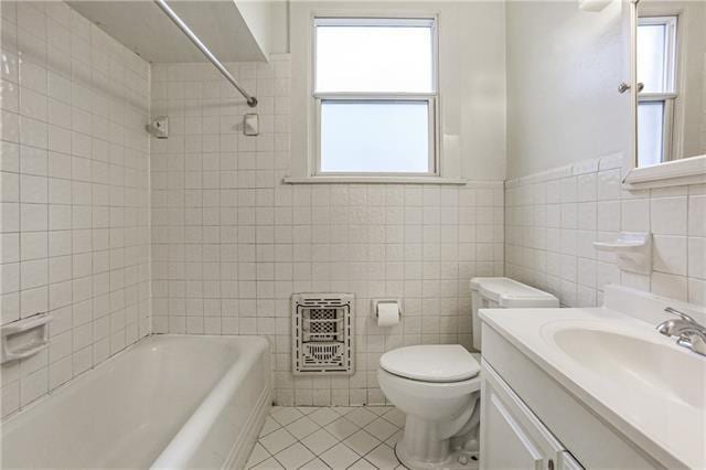 full bathroom featuring toilet, tile walls, vanity, tiled shower / bath combo, and tile patterned flooring