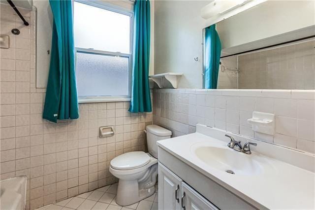 full bathroom featuring vanity, tile patterned floors, toilet, and tile walls