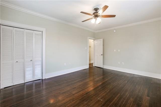 unfurnished bedroom with a closet, ceiling fan, crown molding, and dark hardwood / wood-style flooring