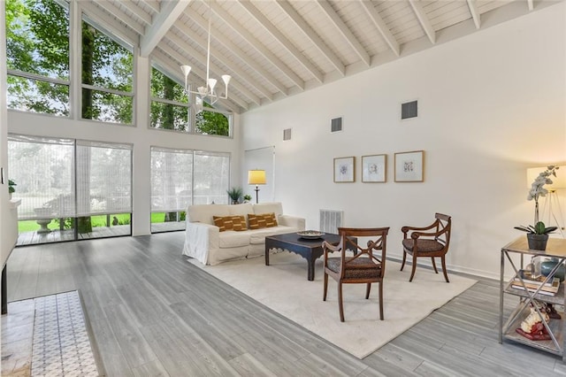 living room featuring beam ceiling, high vaulted ceiling, an inviting chandelier, hardwood / wood-style floors, and wooden ceiling