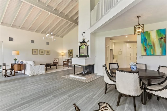 dining area featuring high vaulted ceiling, an inviting chandelier, beamed ceiling, and hardwood / wood-style floors