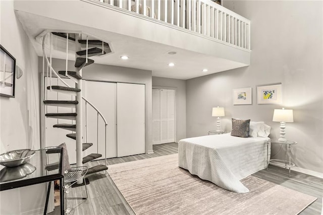 bedroom with hardwood / wood-style flooring, a high ceiling, and a closet