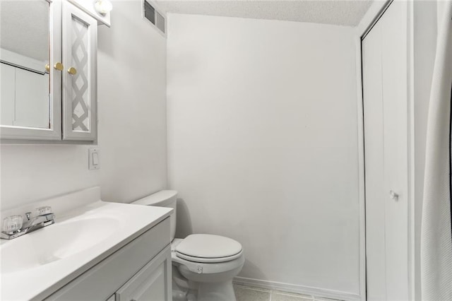 bathroom with tile patterned floors, vanity, toilet, and a textured ceiling