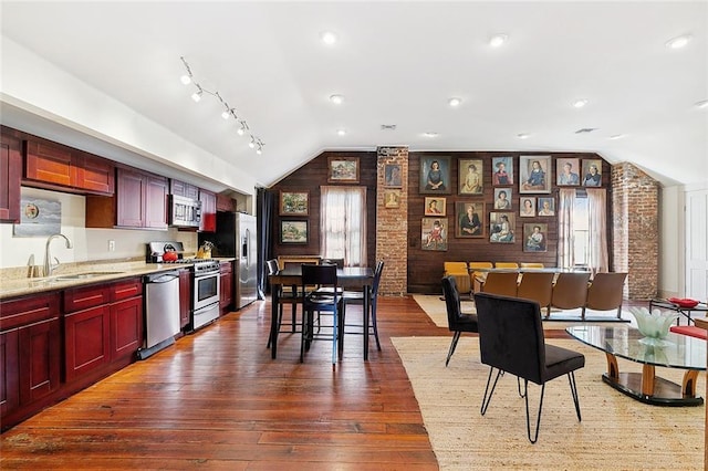 1221 N Tonti St, New Orleans, LA 70119 - kitchen with lofted ceiling, appliances with stainless steel finishes, reddish brown cabinets, dark wood finished floors, and brick wall