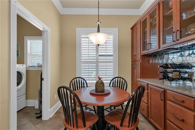 tiled dining room with washer / dryer and crown molding