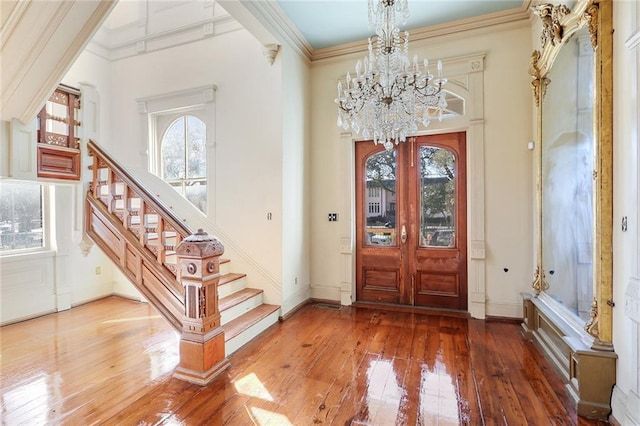 entryway with french doors, wood-type flooring, an inviting chandelier, and ornamental molding