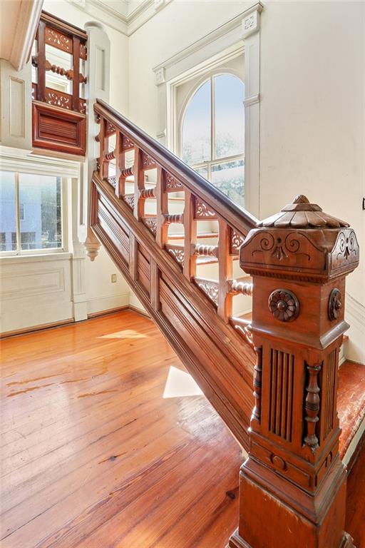 stairway with crown molding and wood-type flooring