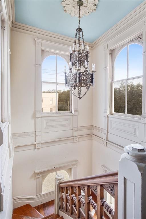 interior space with a wealth of natural light, crown molding, a notable chandelier, and wood-type flooring