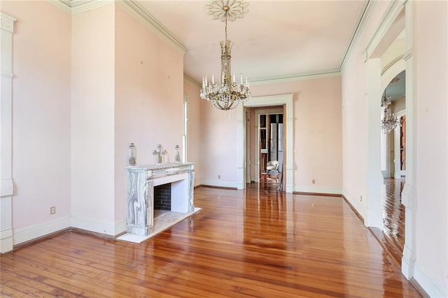 unfurnished living room featuring ornamental molding, wood-type flooring, and an inviting chandelier