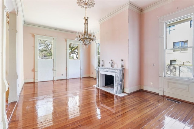 unfurnished living room with wood-type flooring, ornamental molding, and an inviting chandelier