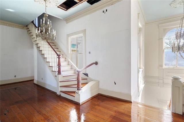 staircase featuring crown molding, a wealth of natural light, a chandelier, and hardwood / wood-style floors