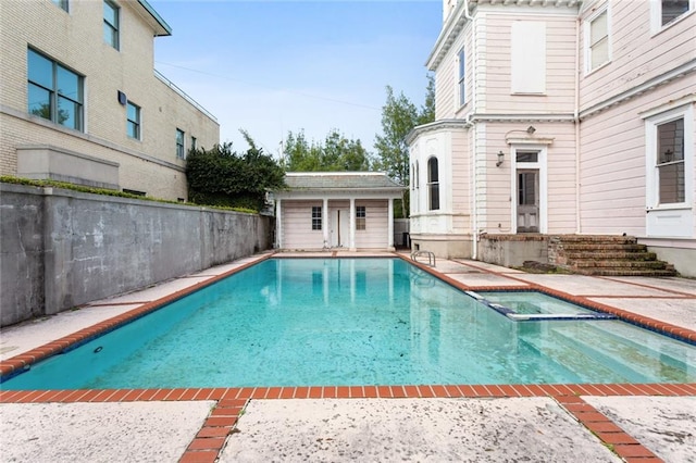 view of swimming pool with a patio, an outbuilding, and an in ground hot tub