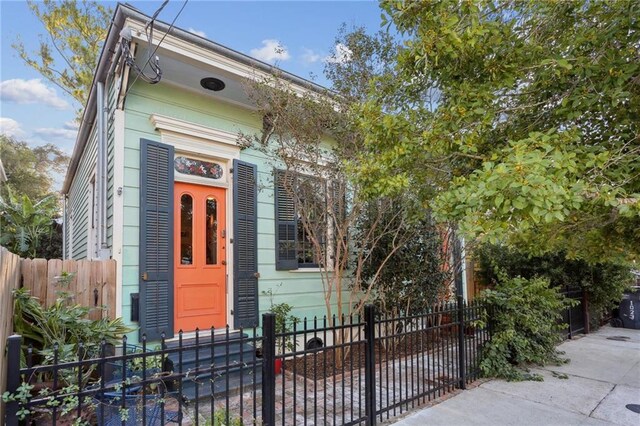 shotgun-style home with entry steps and a fenced front yard