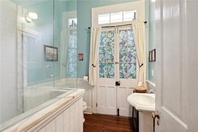 bathroom featuring toilet, shower / bath combination with glass door, a sink, and wood finished floors