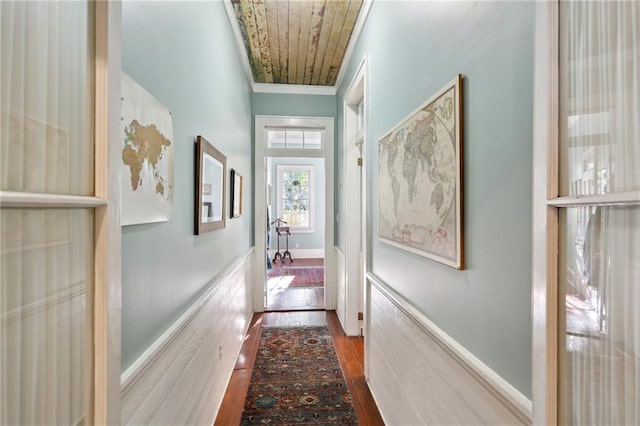 corridor with baseboards, ornamental molding, and dark wood-style flooring