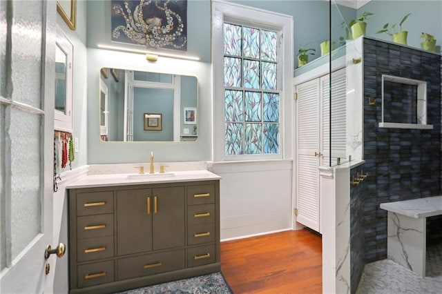 full bath featuring a walk in shower, wood finished floors, and vanity