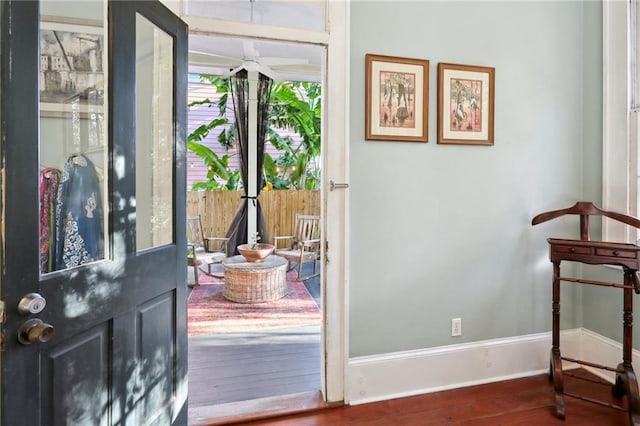 doorway with dark wood-style floors and baseboards