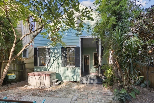 back of property with a patio area, fence, and a hot tub