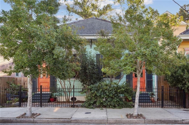 view of front facade featuring a fenced front yard and a shingled roof