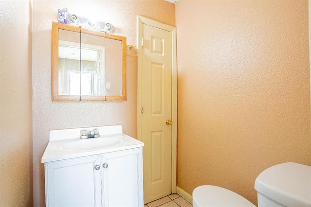 bathroom with toilet, vanity, and tile patterned flooring