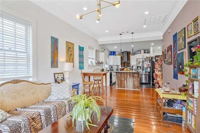 living area featuring hardwood / wood-style flooring, a healthy amount of sunlight, visible vents, and ornamental molding