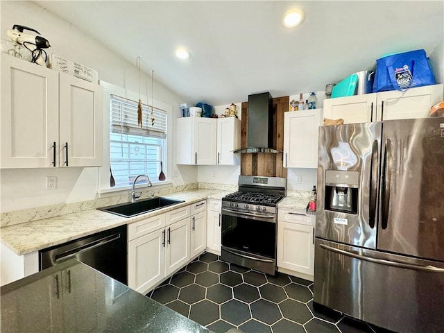 kitchen featuring wall chimney range hood, recessed lighting, appliances with stainless steel finishes, white cabinets, and a sink