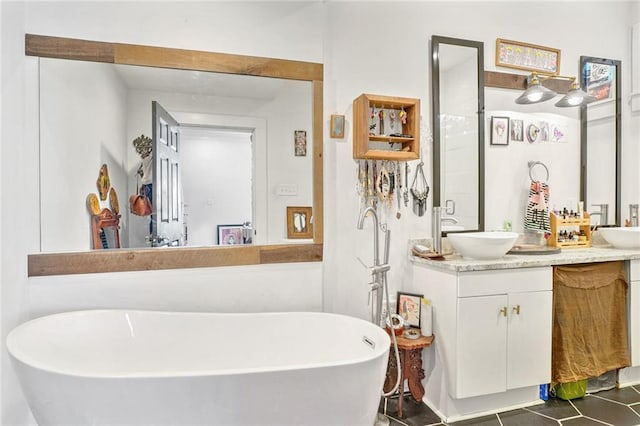 full bath featuring a freestanding tub, vanity, and tile patterned flooring