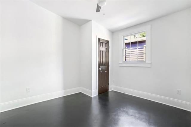 unfurnished room with finished concrete floors, ceiling fan, and baseboards