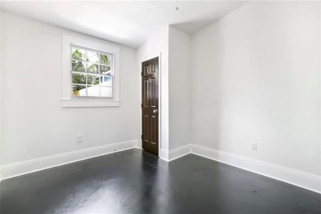 empty room with baseboards and finished concrete flooring