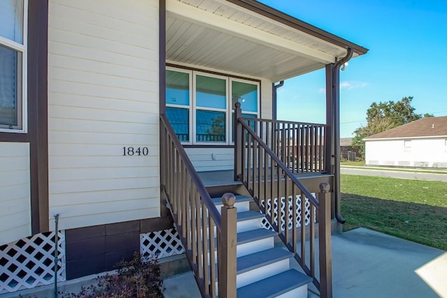 doorway to property featuring a yard and covered porch