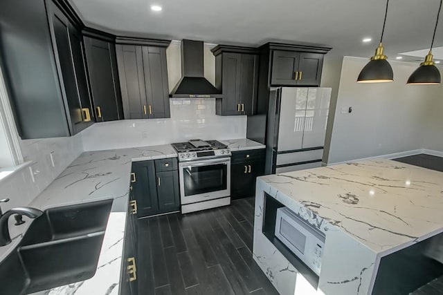 kitchen featuring high end stainless steel range, sink, wall chimney exhaust hood, decorative light fixtures, and white refrigerator