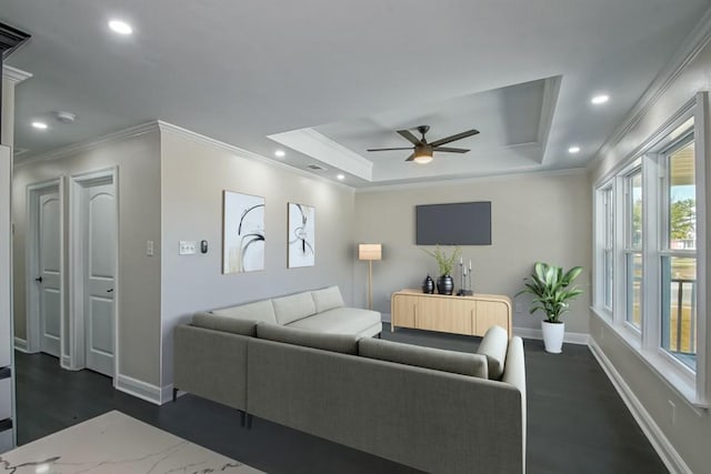 living room with ornamental molding, dark wood-type flooring, a raised ceiling, and ceiling fan