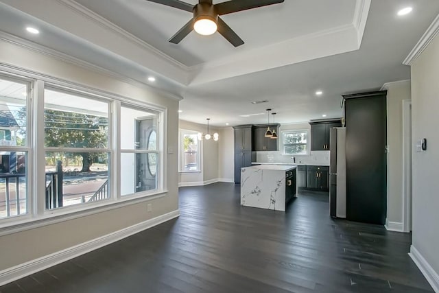 interior space featuring light stone countertops, a center island, dark hardwood / wood-style flooring, stainless steel fridge, and decorative light fixtures