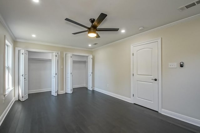 unfurnished bedroom with dark hardwood / wood-style flooring, ornamental molding, multiple closets, and ceiling fan