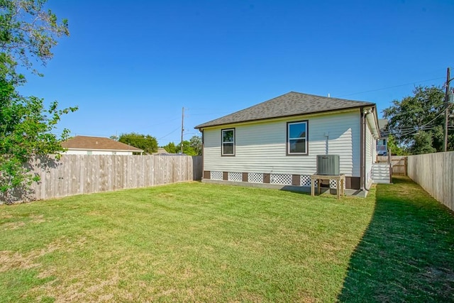 rear view of house featuring a lawn and central AC unit