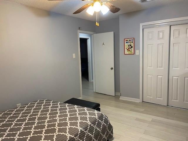 bedroom featuring light hardwood / wood-style flooring, a closet, a textured ceiling, and ceiling fan