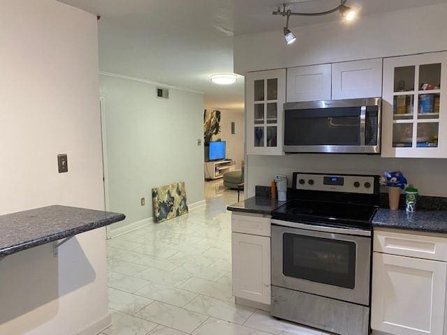 kitchen with white cabinetry, stainless steel appliances, and dark stone counters