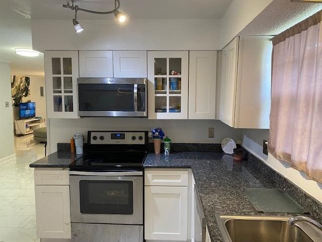 kitchen with sink, white cabinetry, stainless steel appliances, and dark stone counters