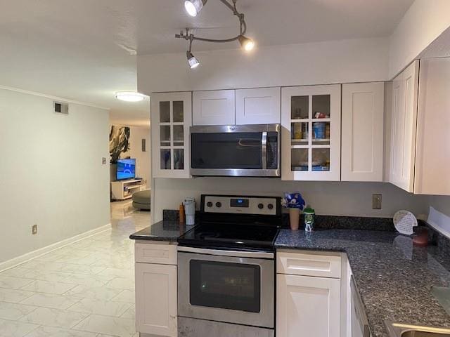 kitchen featuring white cabinetry, stainless steel appliances, rail lighting, and dark stone counters