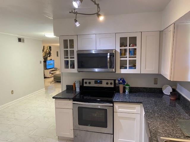 kitchen with white cabinets, a chandelier, stainless steel appliances, and dark stone counters