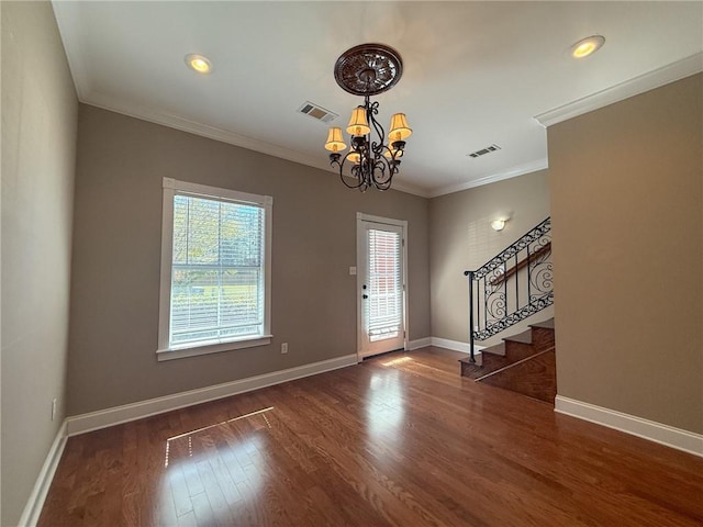 foyer featuring dark hardwood / wood-style flooring, ornamental molding, and an inviting chandelier