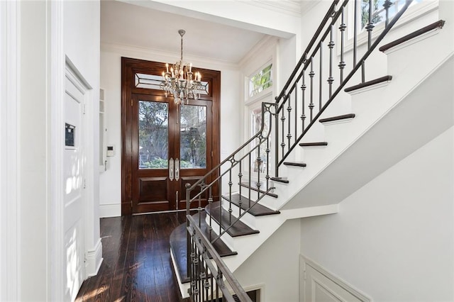 foyer entrance with dark hardwood / wood-style flooring, a chandelier, ornamental molding, and plenty of natural light