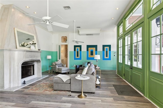 living room with hardwood / wood-style floors, a high end fireplace, ceiling fan, and ornamental molding