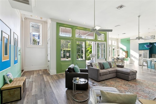 living room with ornamental molding, wood-type flooring, and ceiling fan