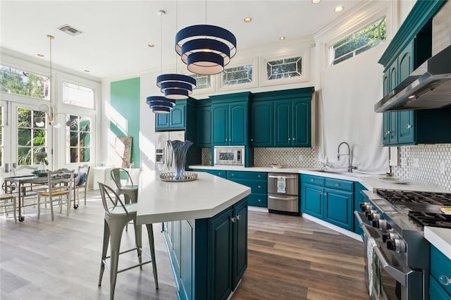 kitchen featuring wood-type flooring, a center island, backsplash, pendant lighting, and high end stainless steel range