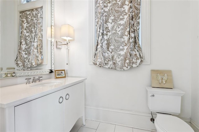 bathroom with toilet, vanity, and tile patterned flooring